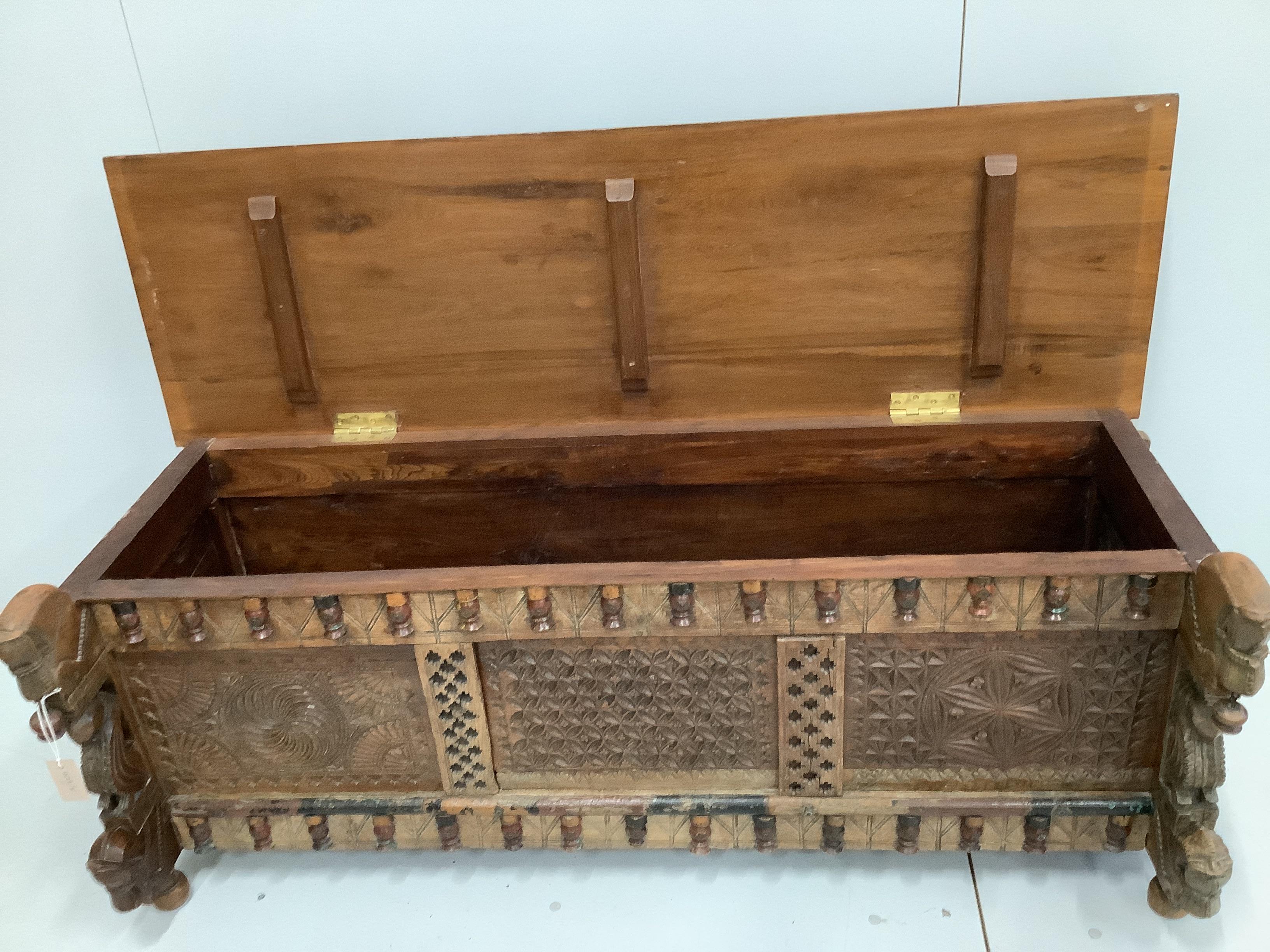 An Indian carved and panelled hardwood low chest, with figural motifs, width 148cm, depth 60cm, height 57cm.